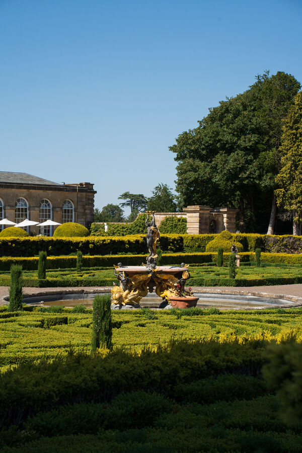 A formal garden with clipped hedges and a fountain